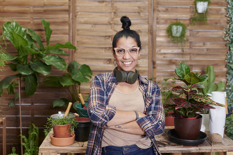 Porträt einer lächelnden jungen Frau bei der Gartenarbeit auf ihrer Terrasse, lizenzfreies Stockfoto