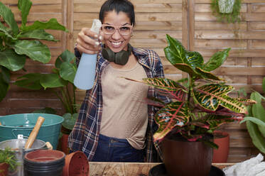 Portrait of a smiling young woman gardening on her terrace - IGGF01391