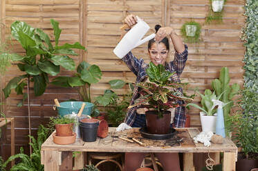 Portrait of a smiling young woman gardening on her terrace - IGGF01392