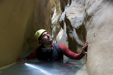 Wanderer, der im Wasser stehend inmitten einer Schlucht nach oben schaut - CAVF68244