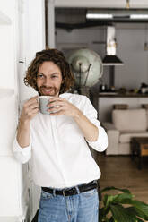 Lächelnder Mann bei einer Kaffeepause zu Hause - GIOF07493
