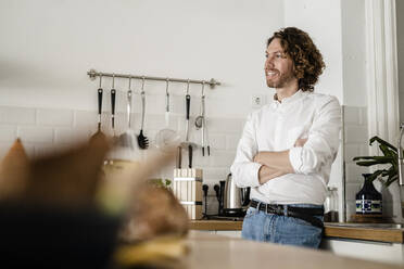 Smiling man standing in kitchen at home - GIOF07522