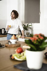 Mann hält ein Glas Orangensaft in der Küche zu Hause - GIOF07523