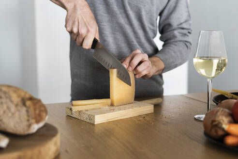 Nahaufnahme eines Mannes, der auf der Küchentheke Käse schneidet - GIOF07528