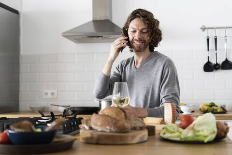 Mann am Telefon in der Küche zu Hause, lizenzfreies Stockfoto
