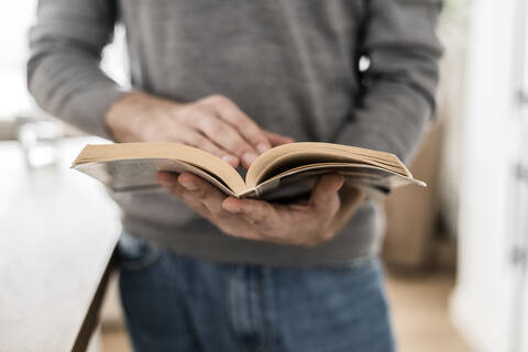 Nahaufnahme eines Mannes, der zu Hause ein Buch liest, lizenzfreies Stockfoto