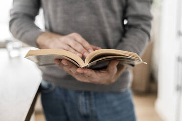 Close-up of man reading book at home - GIOF07536