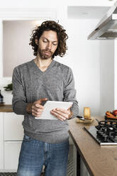 Man using tablet in kitchen at home - GIOF07539