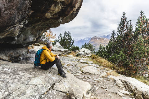 Hiker sitting and looking over alpine plateau in autumn, Sondrio, Italy stock photo