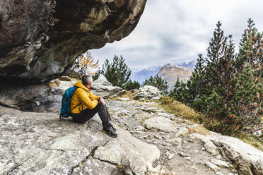 Wanderer im Sitzen und mit Blick auf eine Hochebene im Herbst, Sondrio, Italien - MCVF00064