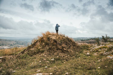 Junger Mann steht auf einem Hügel während eines Sturms, Sizilien - MAMF00941