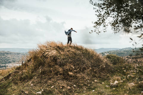 Young man standing on a hill during storm, Sicily stock photo