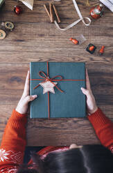 Woman's hands holding Christmas present, from above - MOMF00797