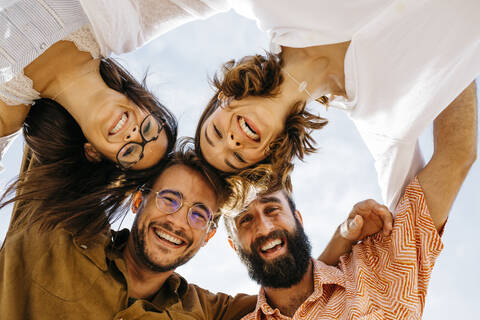 Porträt von glücklichen Freunden, die sich im Freien zusammenkauern, lizenzfreies Stockfoto