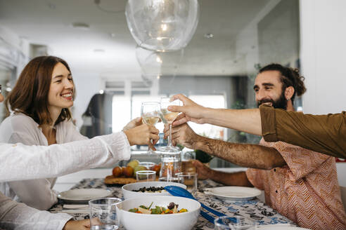 Glückliche Freunde beim gemeinsamen Mittagessen und beim Anstoßen mit Gläsern - JRFF03850