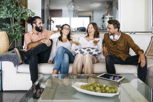 Glückliche Freunde sitzen zusammen auf der Couch und reden - JRFF03865