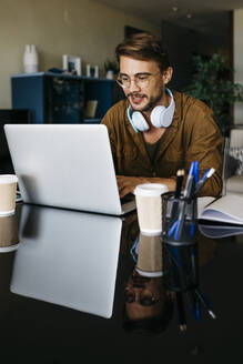 Mann arbeitet zu Hause am Tisch mit Laptop - JRFF03870