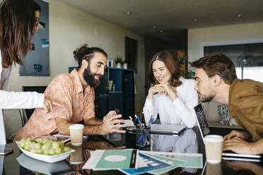 Freunde arbeiten gemeinsam an einem Tisch zu Hause und teilen sich ein Smartphone - JRFF03881