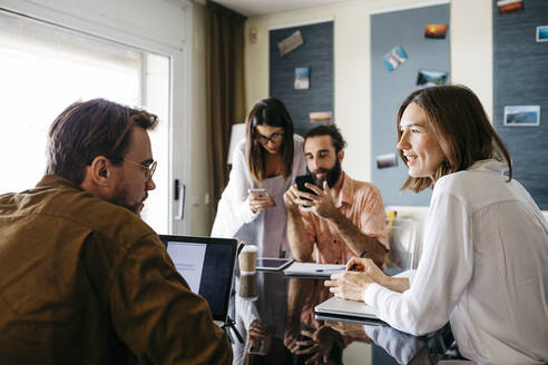 Freunde arbeiten gemeinsam am Tisch zu Hause und unterhalten sich - JRFF03882