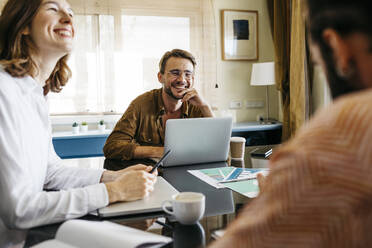 Glückliche Freunde arbeiten gemeinsam am Tisch zu Hause - JRFF03885