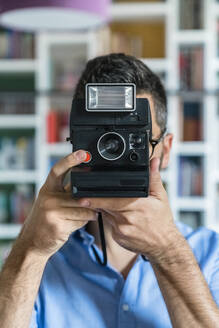 Young man taking photo with instant camera - MGIF00877