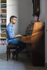 Barfüßiger junger Mann, der zu Hause Klavier spielt - MGIF00879
