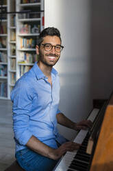 Portrait of happy young man playing piano at home - MGIF00882