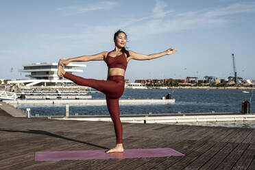 Asiatische Frau, die Yoga praktiziert, auf einem Bein stehend, Hand-zu-Zeh-Pose - RCPF00085