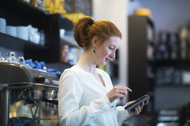 Young woman working in coffee shop, using calculator - SGF02429