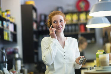 Junge Frau arbeitet in einem Café und benutzt ein Telefon - SGF02430