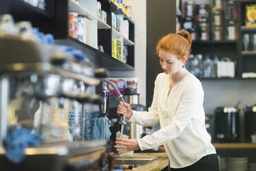 Junge Frau arbeitet in einem Café und wäscht Geschirr - SGF02432