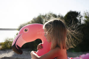 Mädchen umarmt Flamingo-Poolschwimmer - EYAF00640