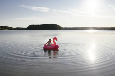 Mädchen mit Flamingo-Poolschwimmer auf einem See - EYAF00644