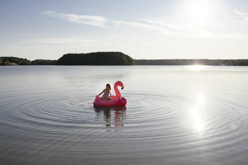 Girl with flamingo pool float on a lake - EYAF00644