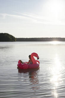 Mädchen mit Flamingo-Poolschwimmer auf einem See - EYAF00645