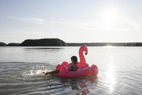 Mädchen mit Flamingo-Poolschwimmer auf einem See - EYAF00646