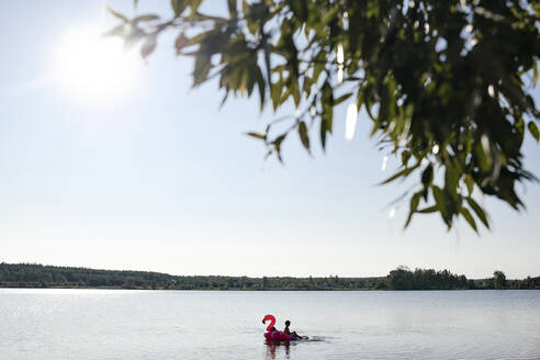 Ein Junge mit Flamingo-Poolschwimmer auf einem See - EYAF00654