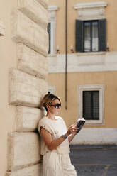 Frau schaut in einen Reiseführer in der Stadt, Rom, Italien - EYAF00668