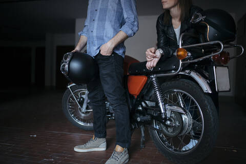 Ehepaar mit Oldtimer-Motorrad in der Garage, lizenzfreies Stockfoto