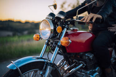 Ausschnittaufnahme eines Paares auf einem Oldtimer-Motorrad bei Sonnenuntergang - JPIF00249