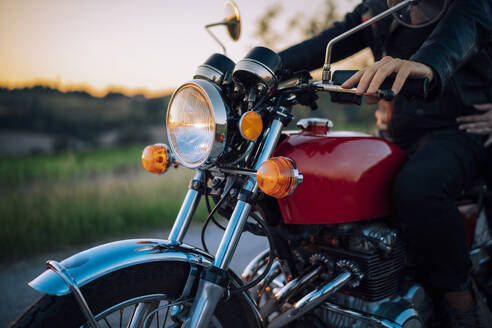 Crop shot of couple on vintage motorbike at sunset - JPIF00249