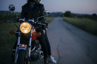 Ausschnittaufnahme eines jungen Paares auf einem alten Motorrad am Straßenrand - JPIF00260
