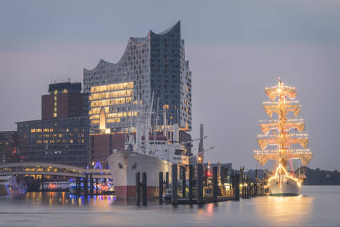 Deutschland, Hamburg, Mexikanisches Segelschulschiff Cuauhtemoc in der Abenddämmerung auf dem Fluss nahe der Elbphilharmonie - KEBF01413