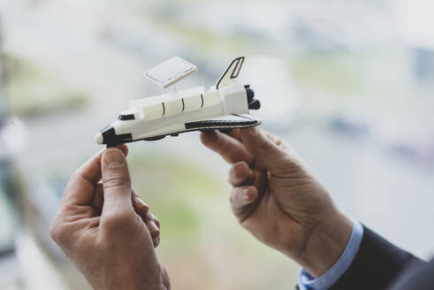 Close-up of bussinessman holding space shuttle model - MOEF02510