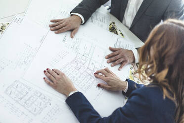 Close-up of businesswoman and businessman working on plan on desk in office - MOEF02529