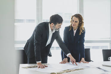 Businesswoman and businessman working on plan on desk in office - MOEF02543