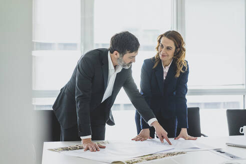 Geschäftsfrau und Geschäftsmann arbeiten an einem Plan auf dem Schreibtisch im Büro - MOEF02543