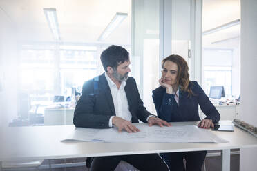 Geschäftsfrau und Geschäftsmann arbeiten an einem Plan auf dem Schreibtisch im Büro - MOEF02574