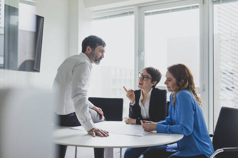 Geschäftsmann und zwei Geschäftsfrauen arbeiten an einem Plan auf dem Schreibtisch im Büro, lizenzfreies Stockfoto