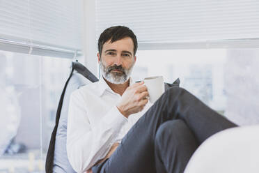 Portrait of mature businessman having a coffee break - MOEF02625